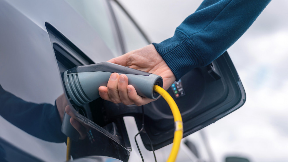 Man plugging in charger into an electric car at charge station scaled